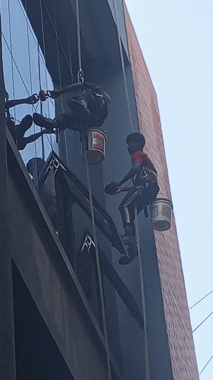 Certified rope access technician cleaning exterior high-rise window